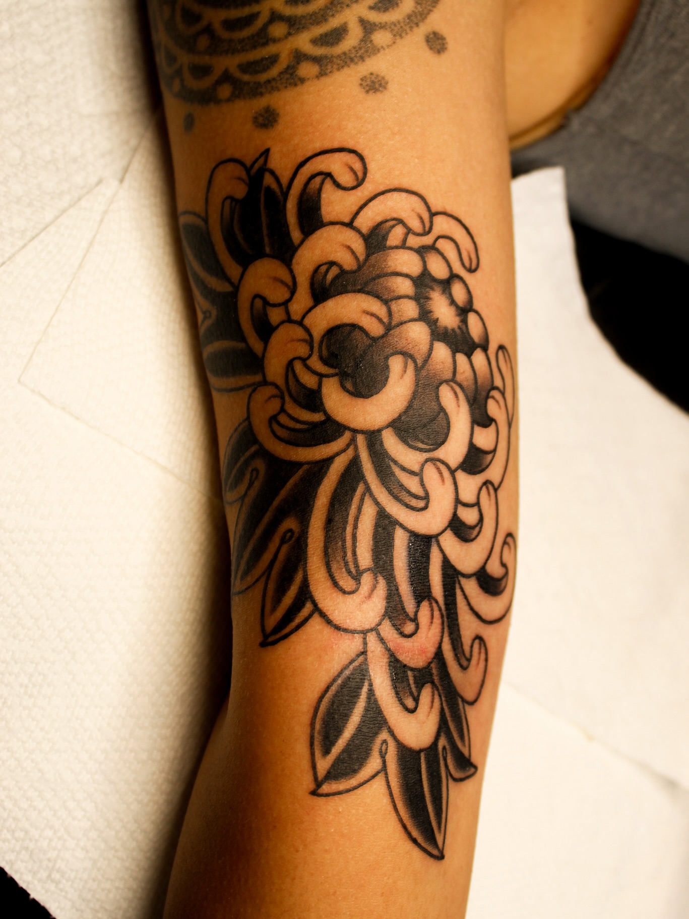 Chrysanthemum black and grey tattoo on the forearm by Kehrmie Tattoos, Berkeley, California