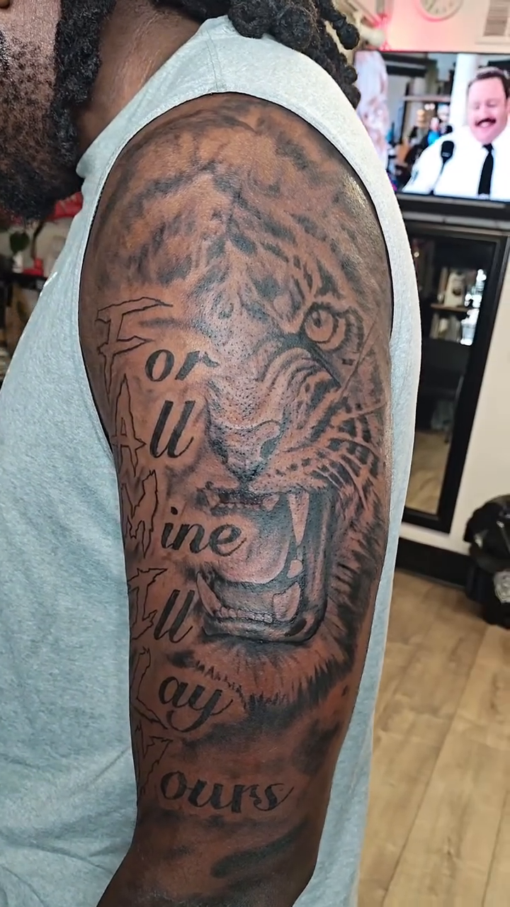 Tiger head with text realism tattoo on the upper arm by @cvpital