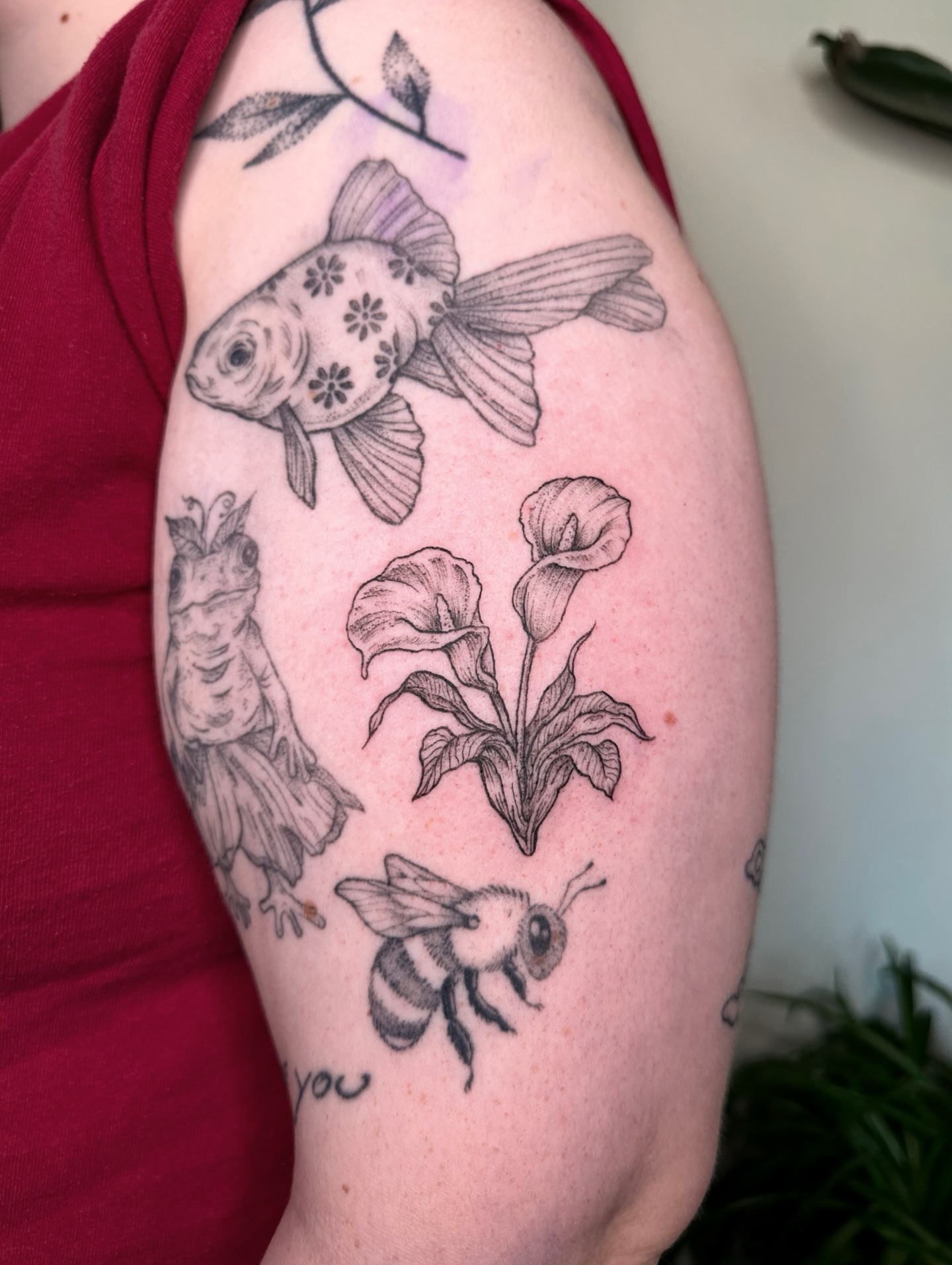Goldfish, flowers, bee black and grey tattoo on the forearm by kenzie hunter