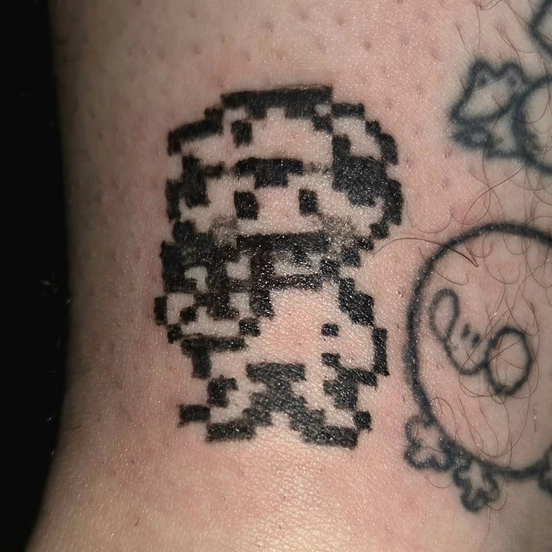 Pixelated character new school tattoo on the forearm by π«