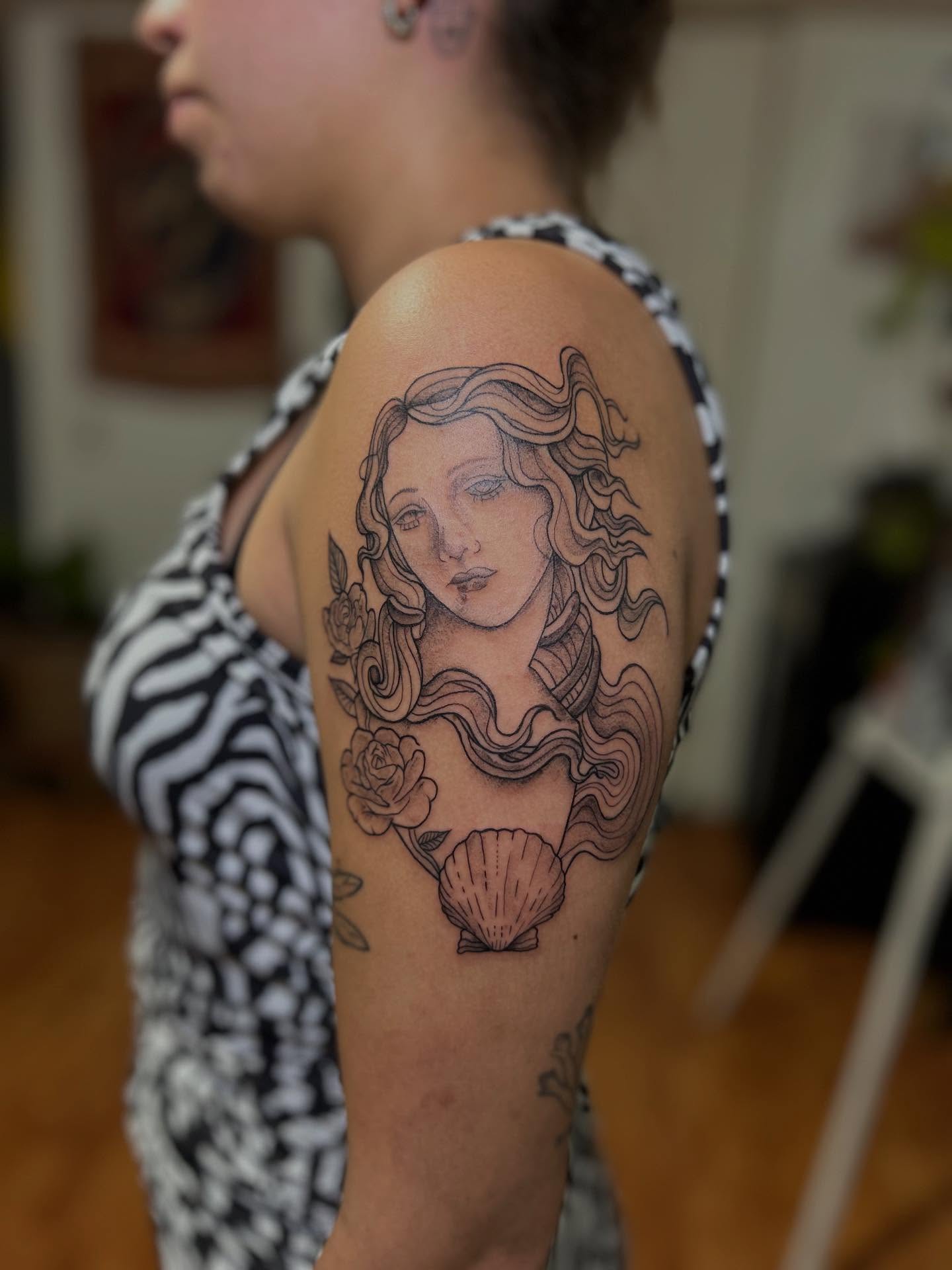 Woman with long hair black and grey tattoo on the shoulder by Barro