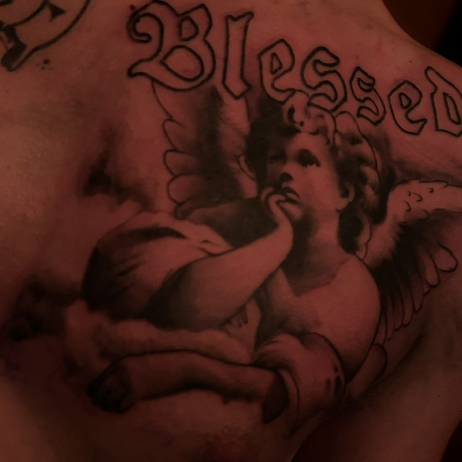 Angel holding baby black and grey tattoo on the chest by Carlos