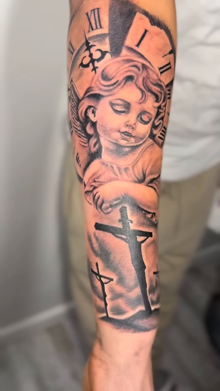 Cherub with clock and crosses realism tattoo on the forearm by Luis Cabrera, Cleveland, Ohio