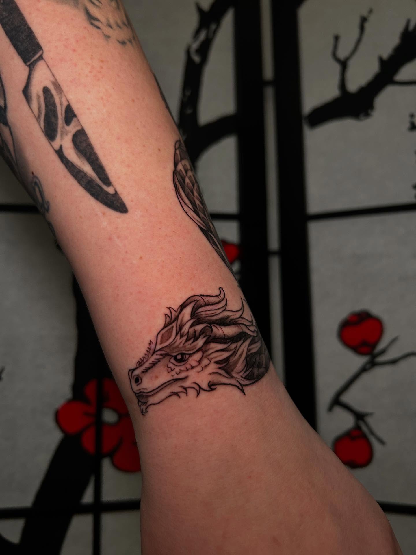 Dragon head black and grey tattoo on the forearm by Chloe