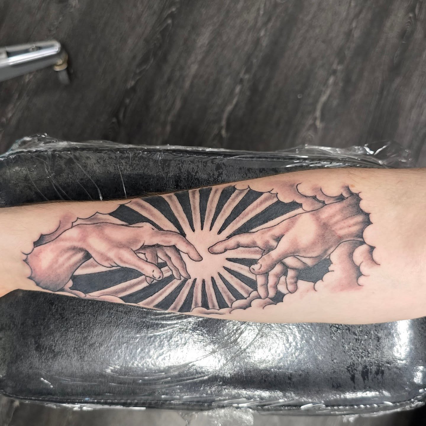 Hands reaching towards each other black and grey tattoo on the forearm by Columbus tattoo artist