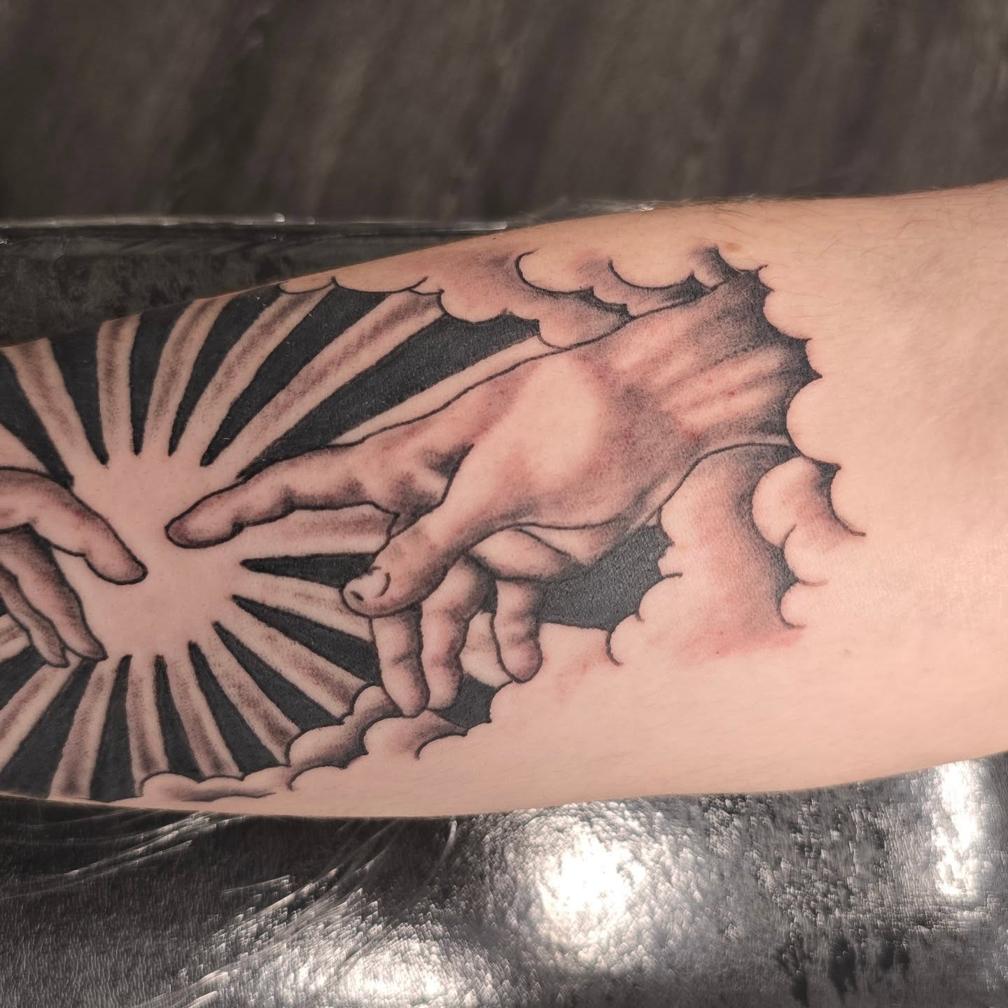 Hands reaching through clouds realism tattoo on the forearm by Columbus tattoo artist