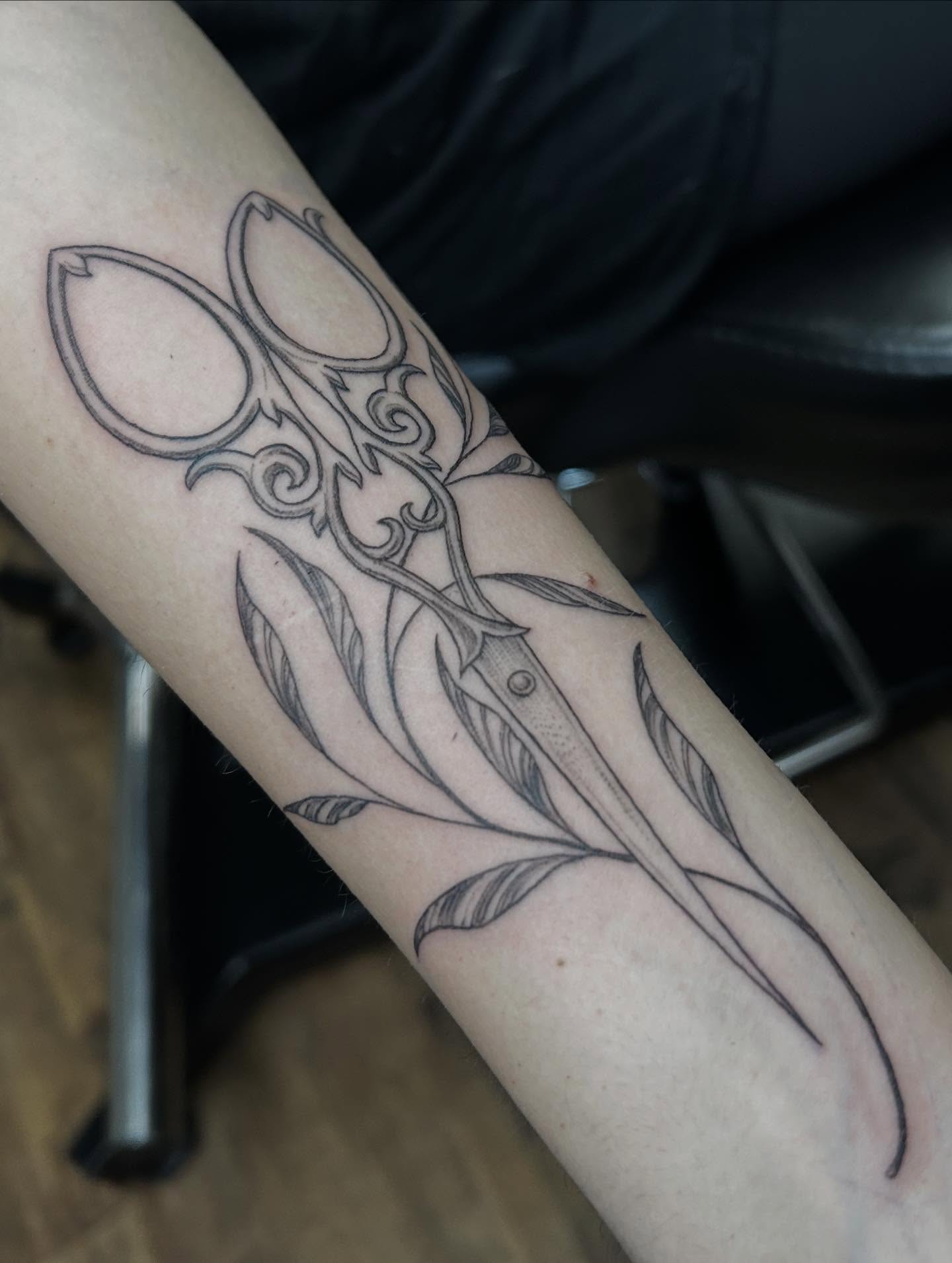 Scissors and leaves black and grey tattoo on the forearm by Ashlee Mshar