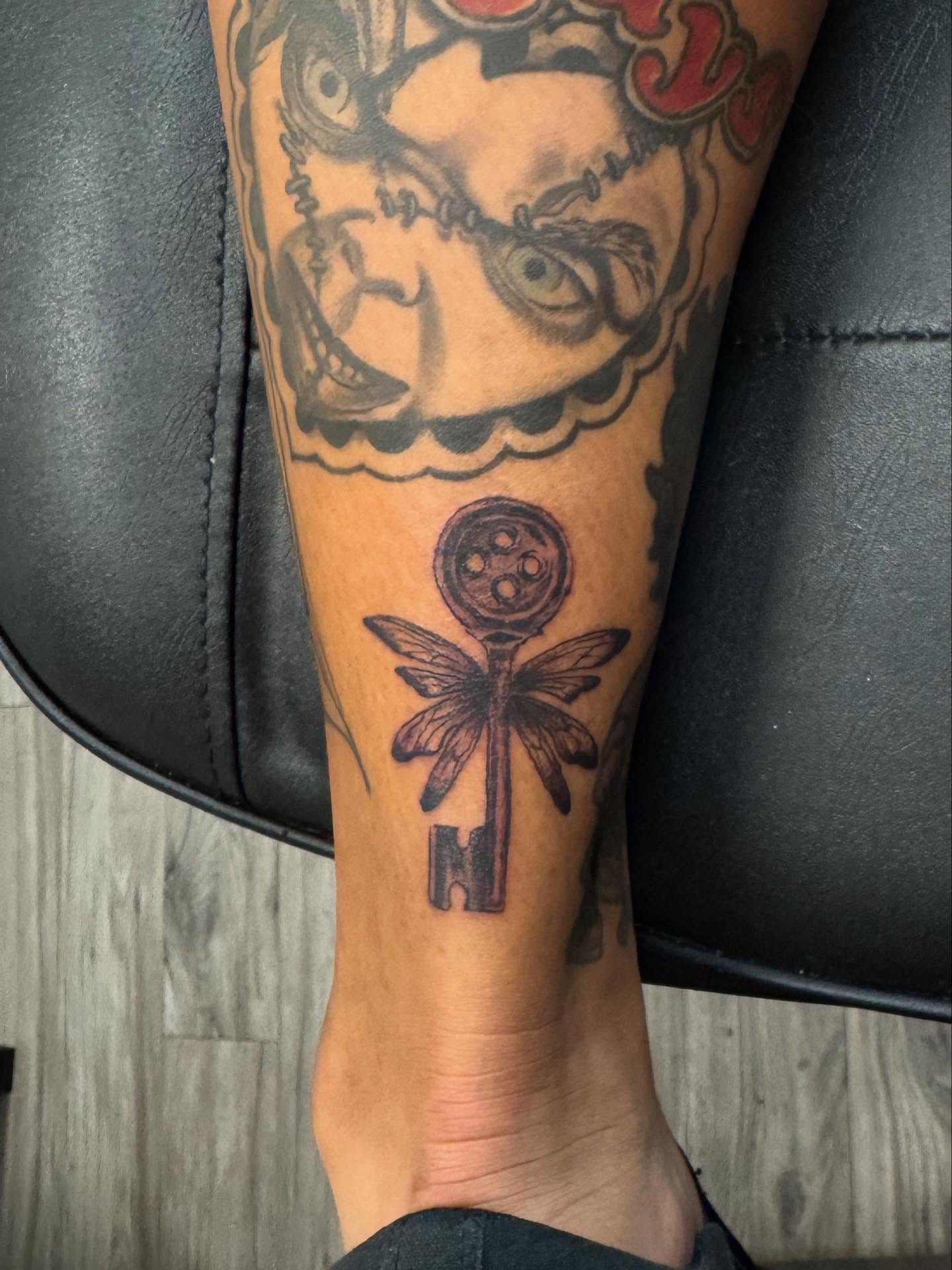 Key with dragonfly black and grey tattoo on the forearm by Gladys L.