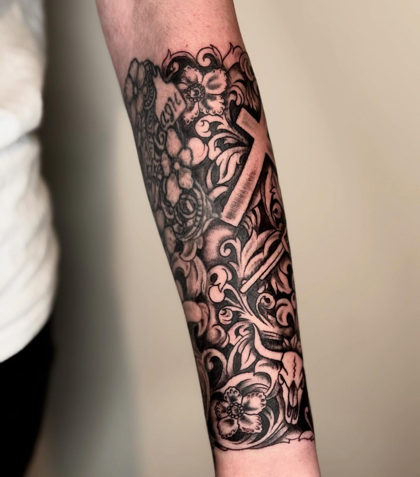 Cross with floral and skull elements Chicano tattoo on the forearm by Elmer Lethco