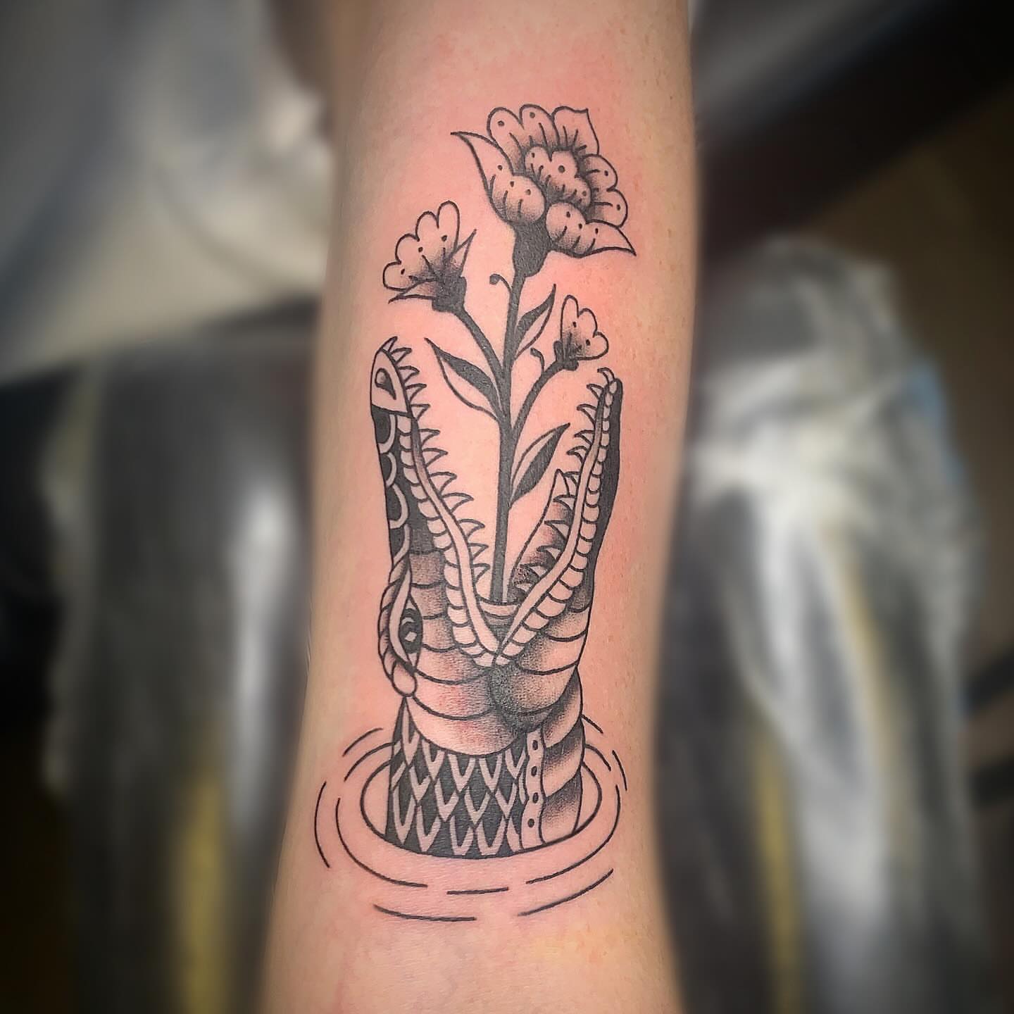 Snake and flowers black and grey tattoo on the forearm by Ava Glory Tattoos