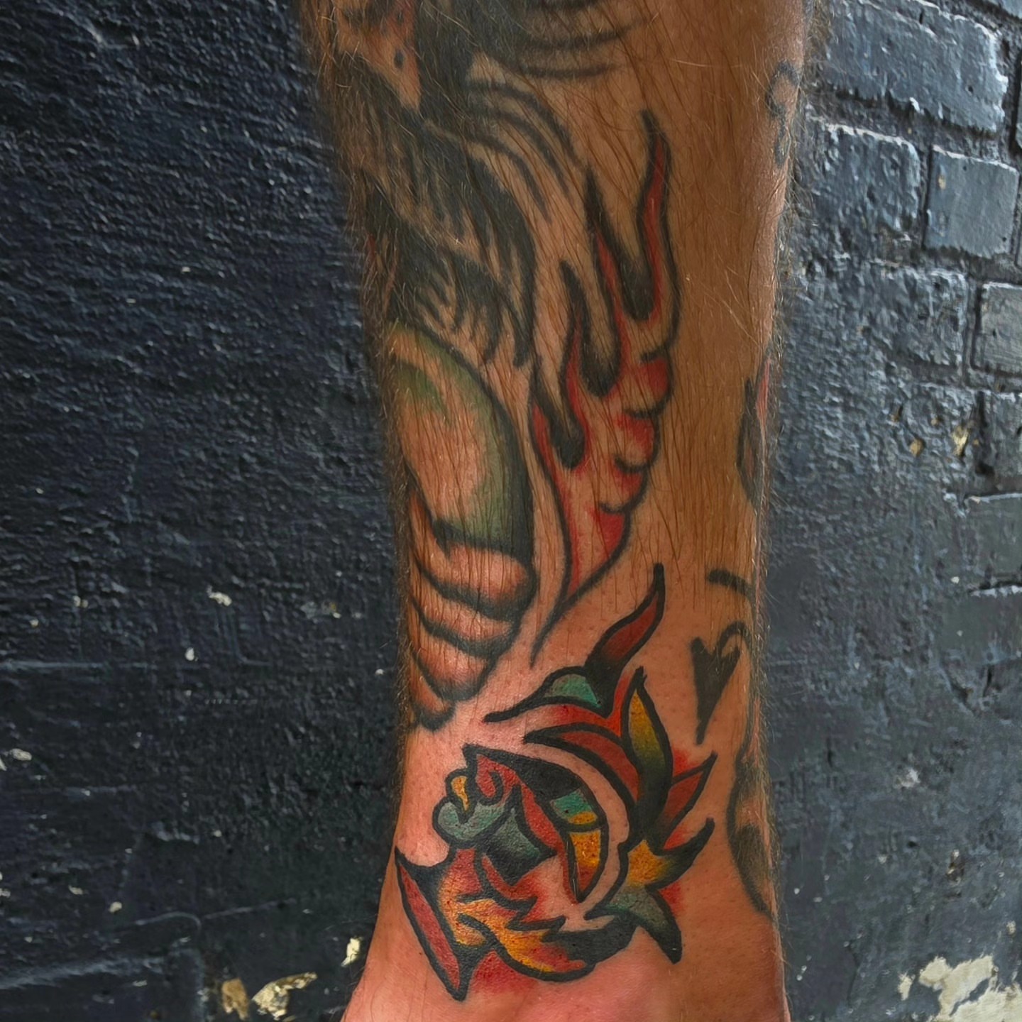 Flaming rose American traditional tattoo on the forearm by Mitch Braver
