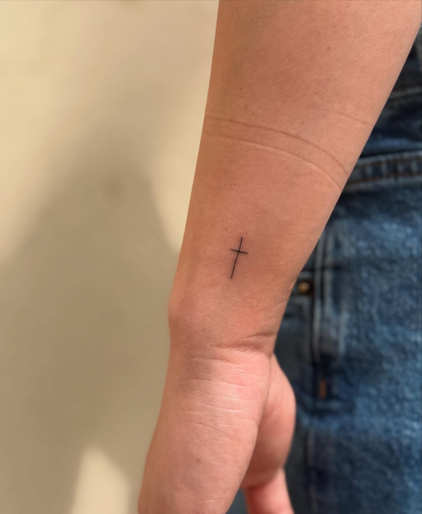 Cross fine line tattoo on the forearm by Kylee Snow