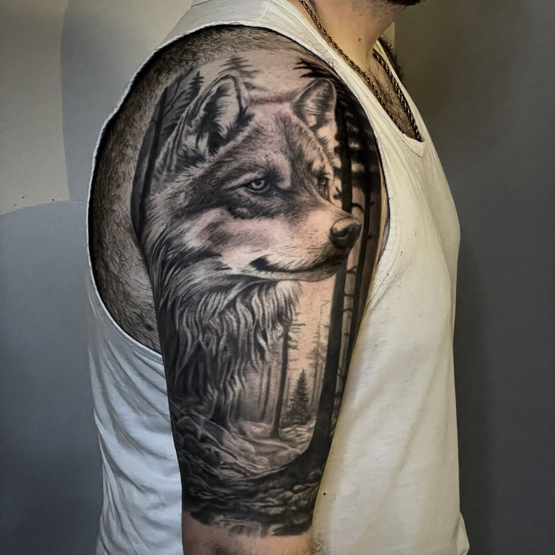 Wolf in forest realism tattoo on the upper arm by Charlie