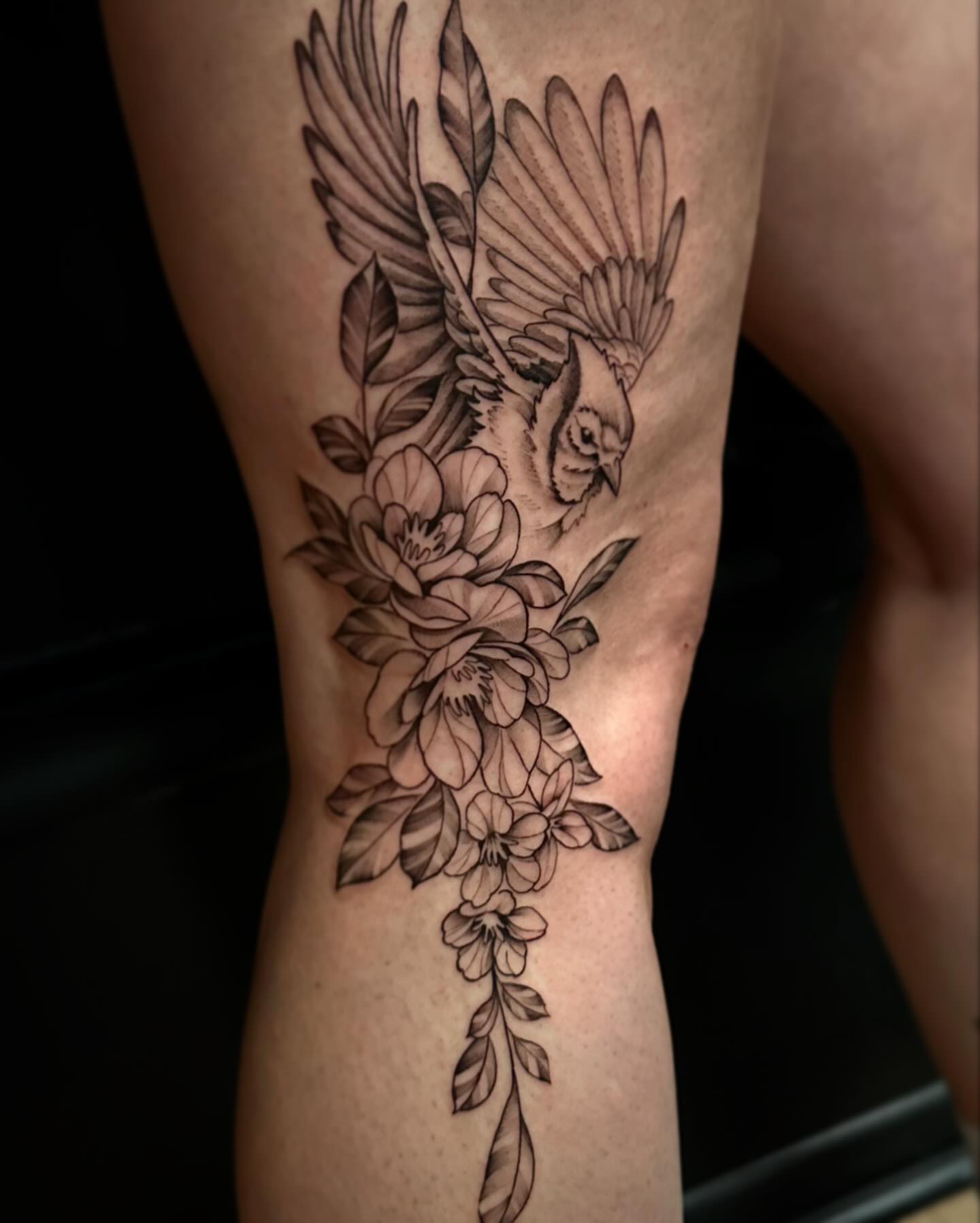 Bird and floral bouquet realism tattoo on the thigh by Sebastian Livingston