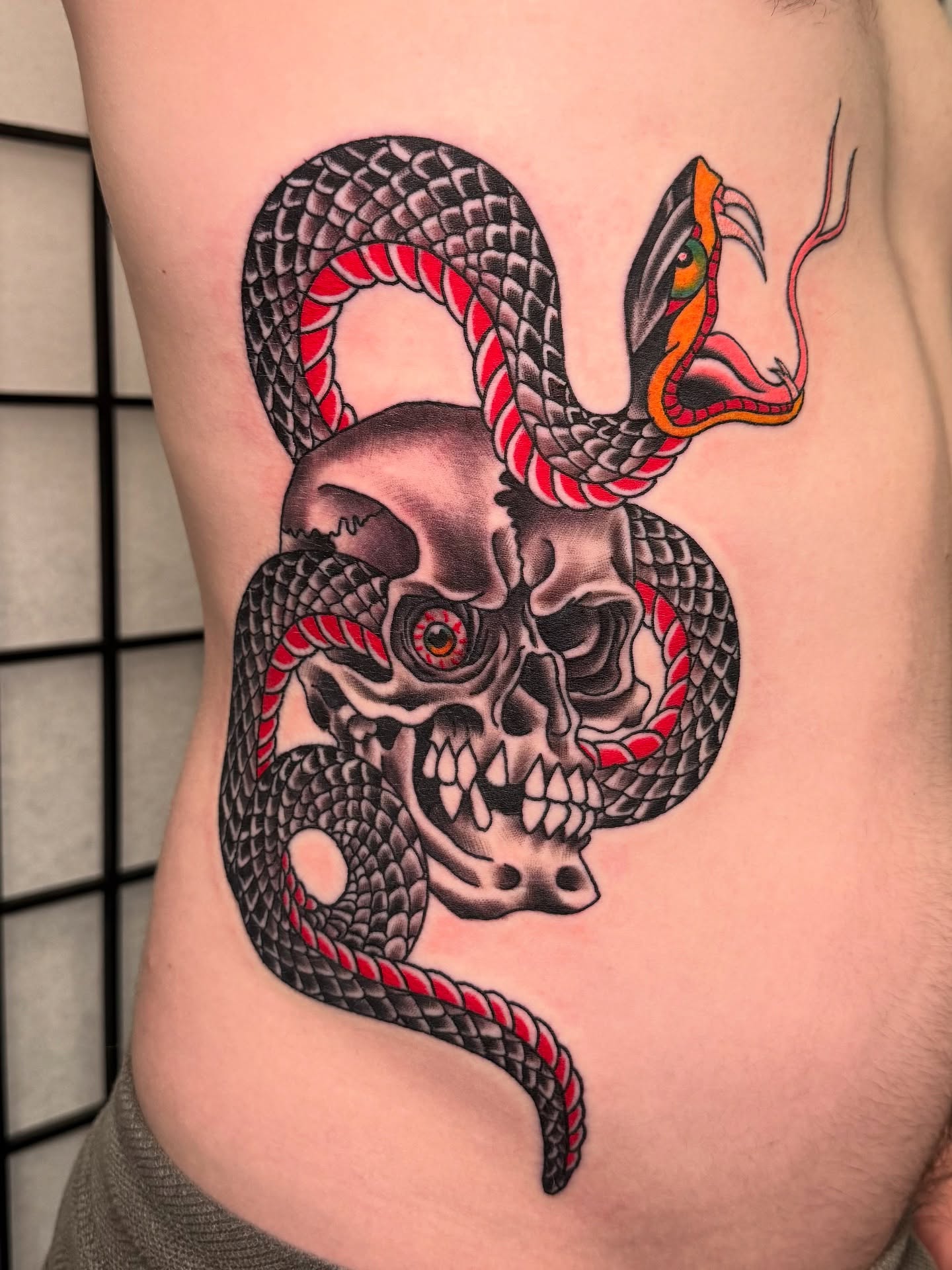 Snake and skull American traditional tattoo on the ribs by 𝕯𝖗𝖊𝖜 𝕲𝖎𝖑𝖊𝖘 𝕵𝖆𝖙𝖙𝖔𝖔, Addison, Texas