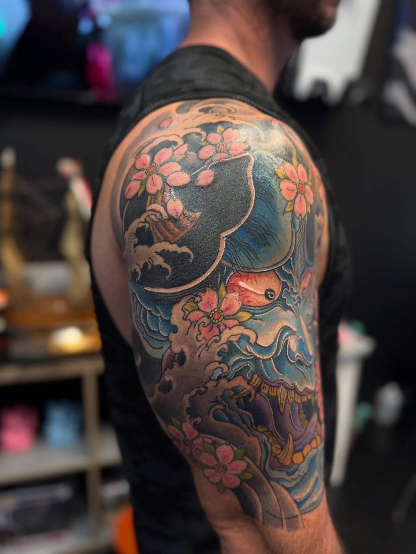 Wave and cherry blossoms japanese irezumi tattoo on the upper arm by Zack Yang, Houston, Texas