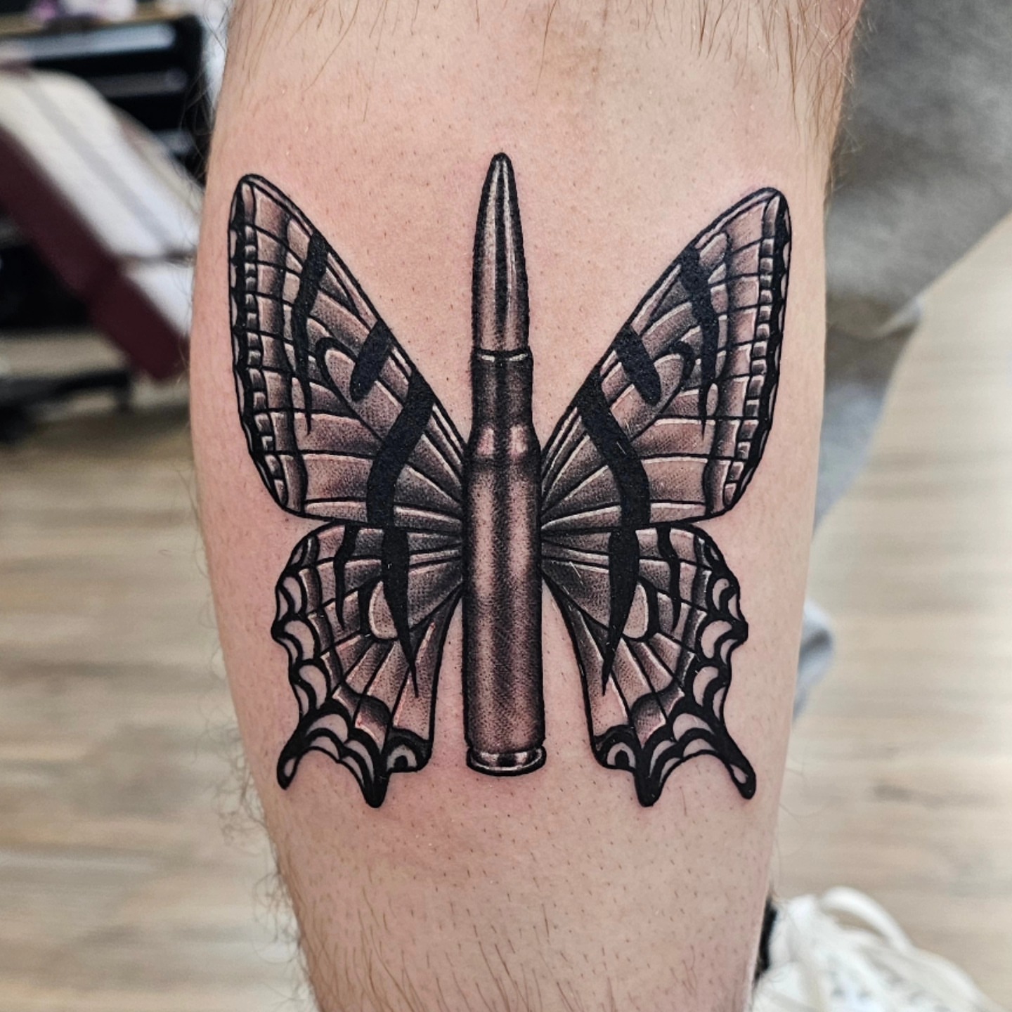 Bullet and butterfly black and grey tattoo on the forearm by Derek Davis