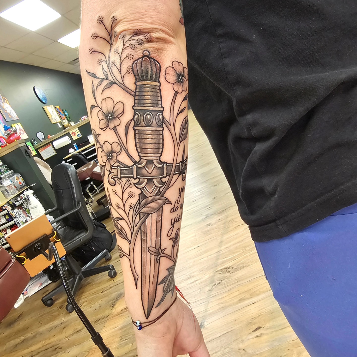Sword and flowers black and grey tattoo on the forearm by Derek Davis