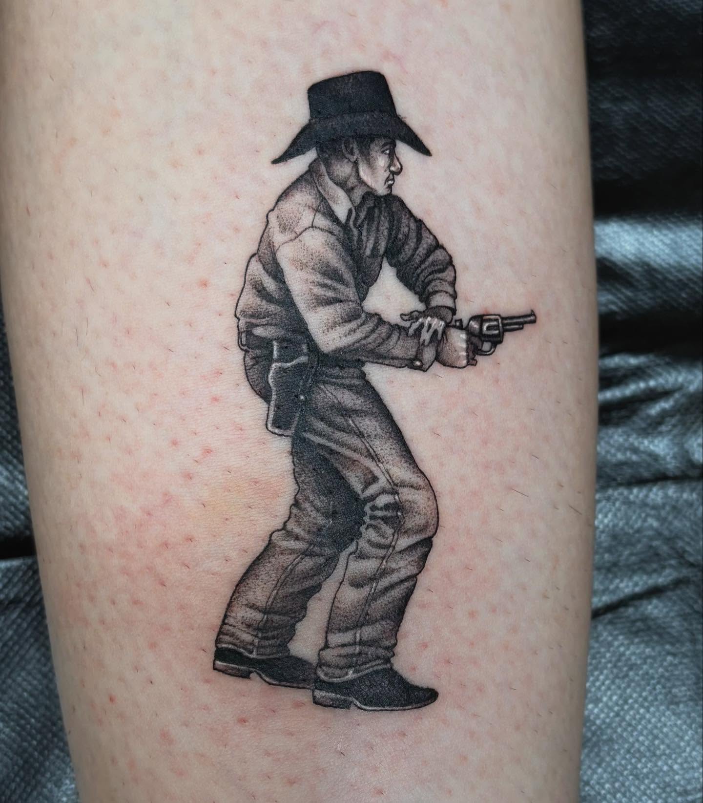 Cowboy with revolver black and grey tattoo on the forearm by Tad Fulkerson, San Francisco, California