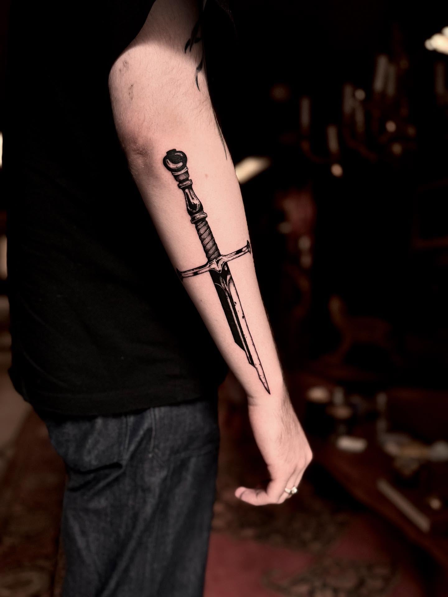 Sword black and grey tattoo on the forearm by 𝐋𝐢𝐬𝐚 𝐊𝐨𝐫𝐳𝐞𝐧𝐨𝐰𝐬𝐤𝐢
