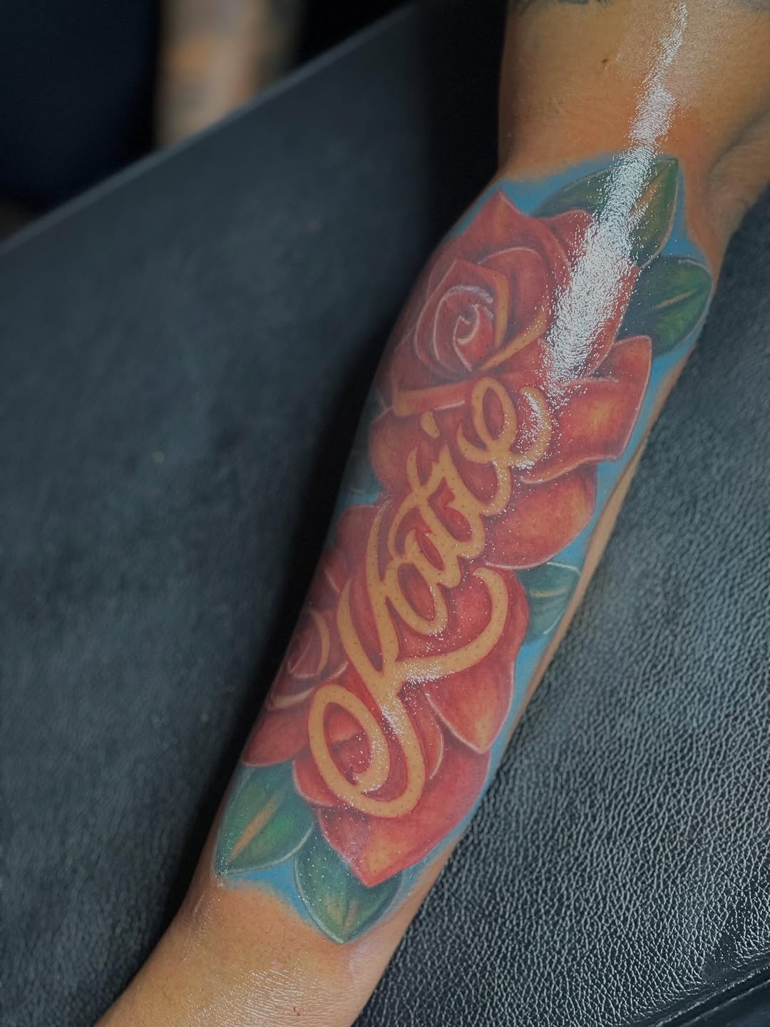 Name 'Katie' with roses lettering tattoo on the forearm by Azaan (Zanye), Birmingham, Alabama
