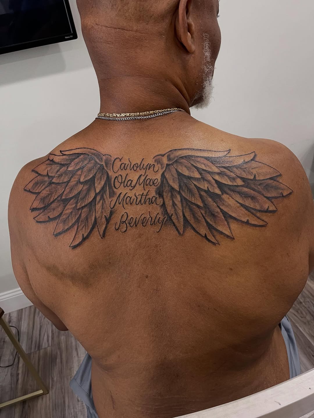 Angel wings with names lettering tattoo on the back by Azaan (Zanye), Birmingham, Alabama