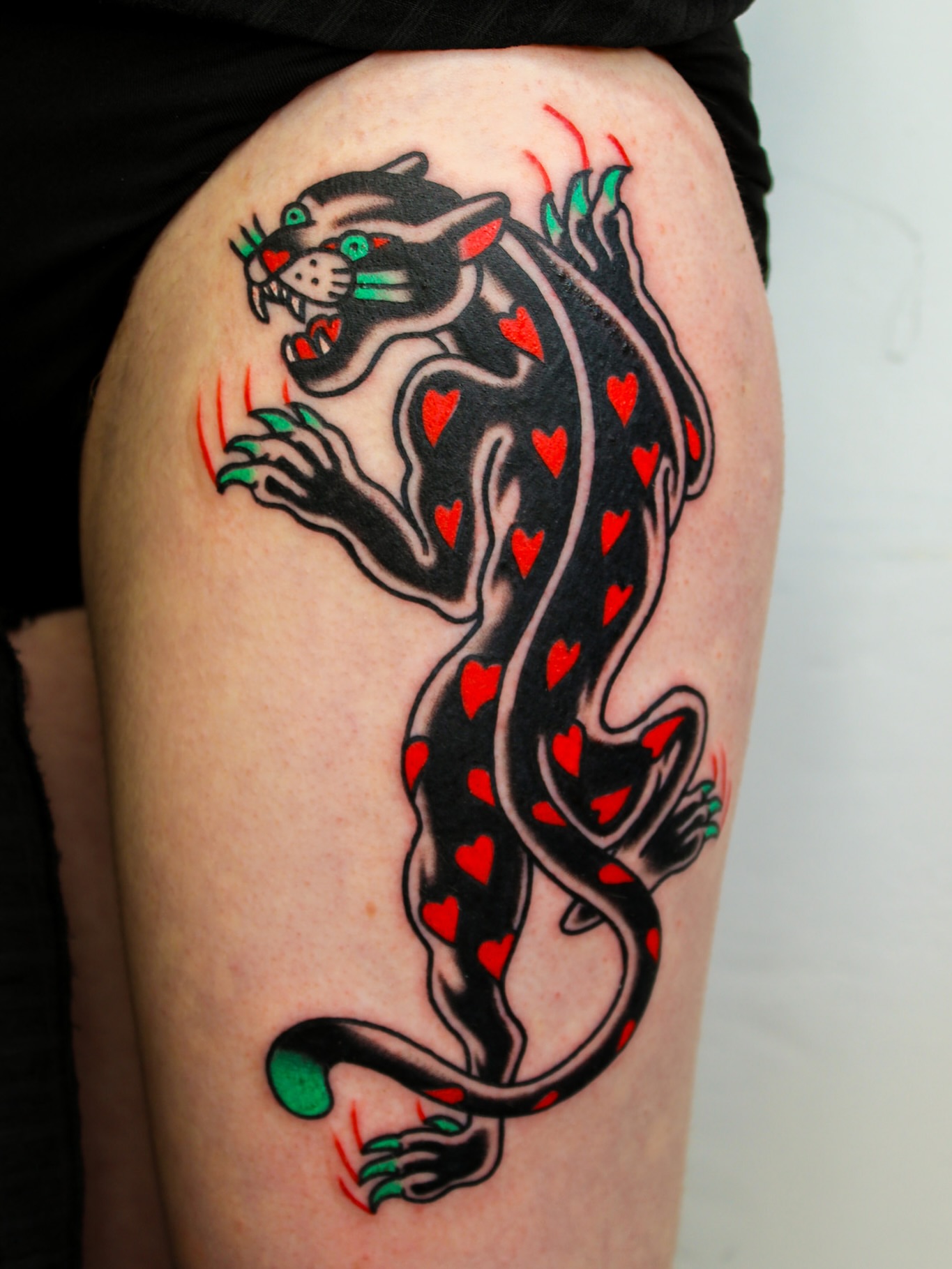 Panther with hearts American traditional tattoo on the thigh by Kehrmie Tattoos, Berkeley, California