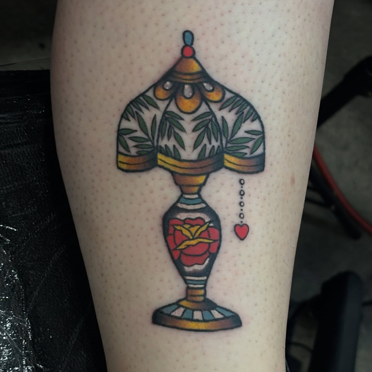Lamp with floral design American traditional tattoo on the forearm by Jordan Wray