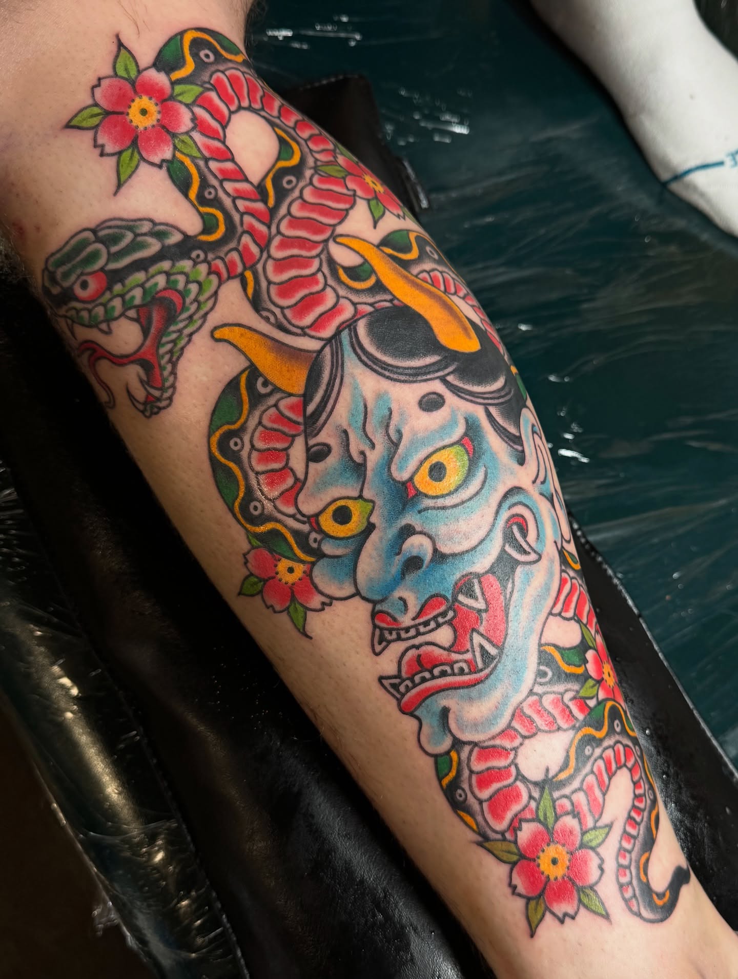 Demon mask and snake American traditional tattoo on the forearm by Ben Karnofsky