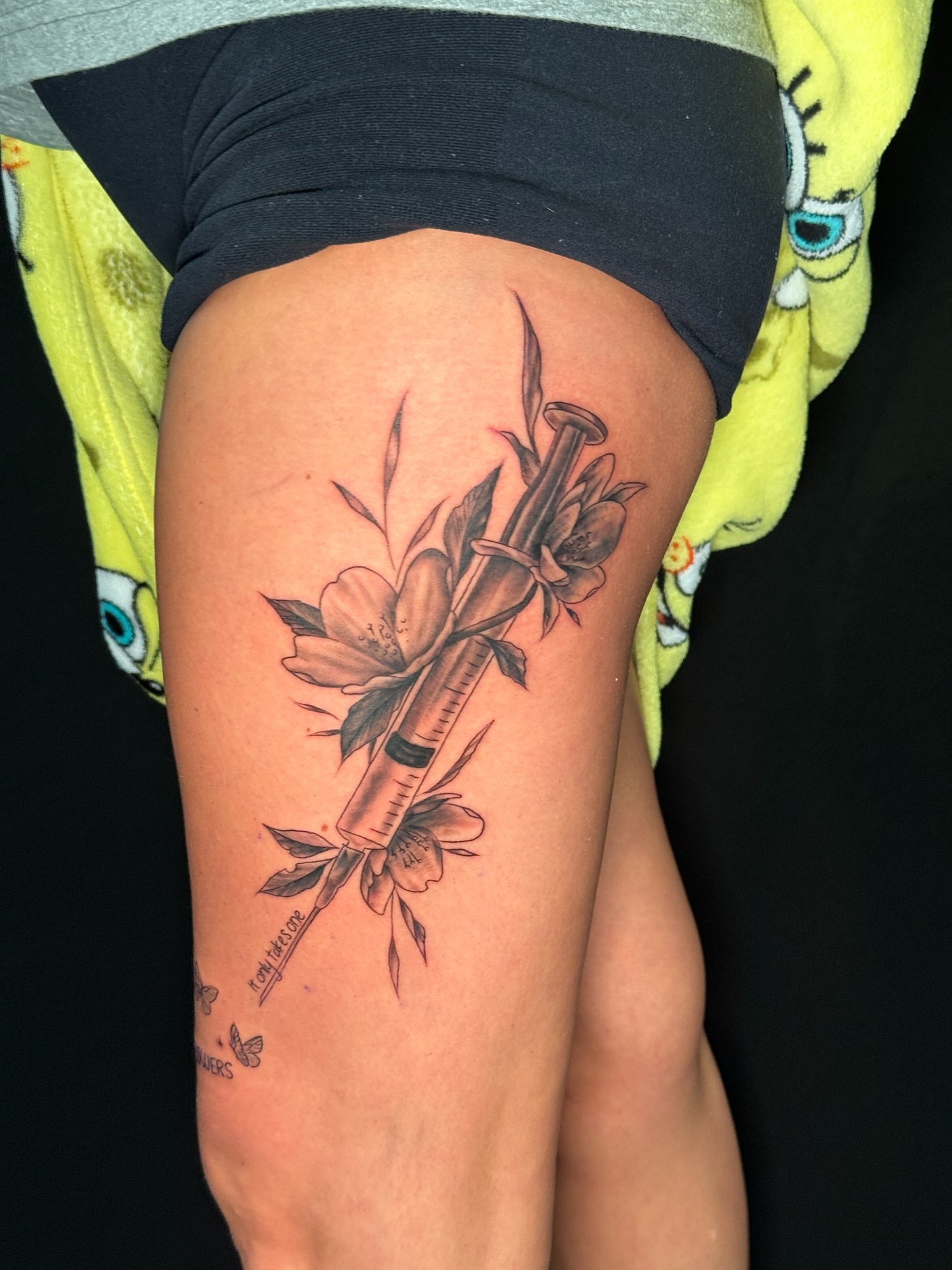 Flower and syringe black and grey tattoo on the thigh by Trevor Sibary