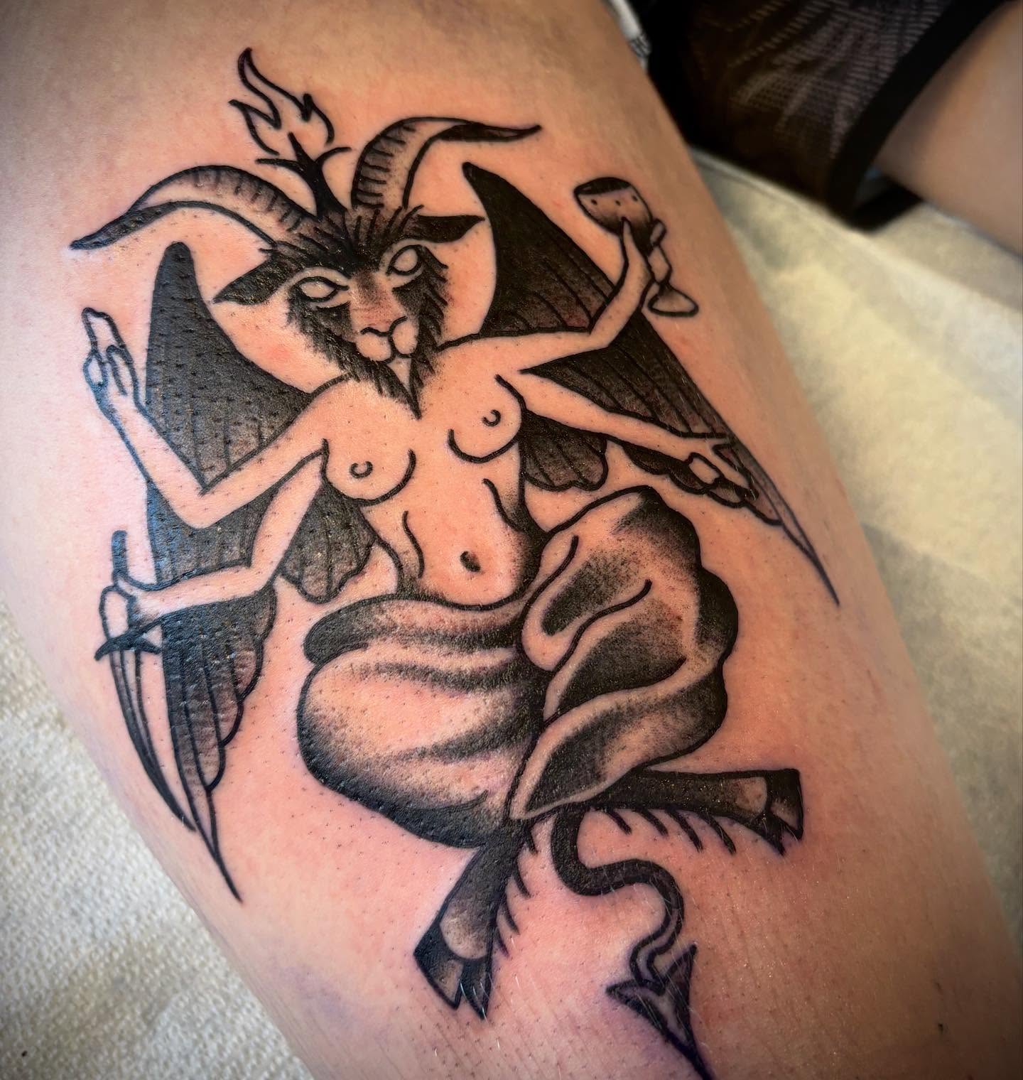 Goat-headed woman with snake black and grey tattoo on the thigh by Nolan Croteau