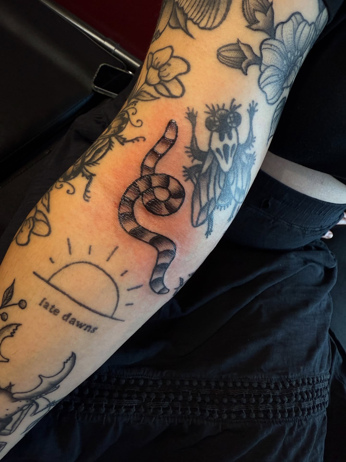 Snake and creature black and grey tattoo on the forearm by Stevie Reign