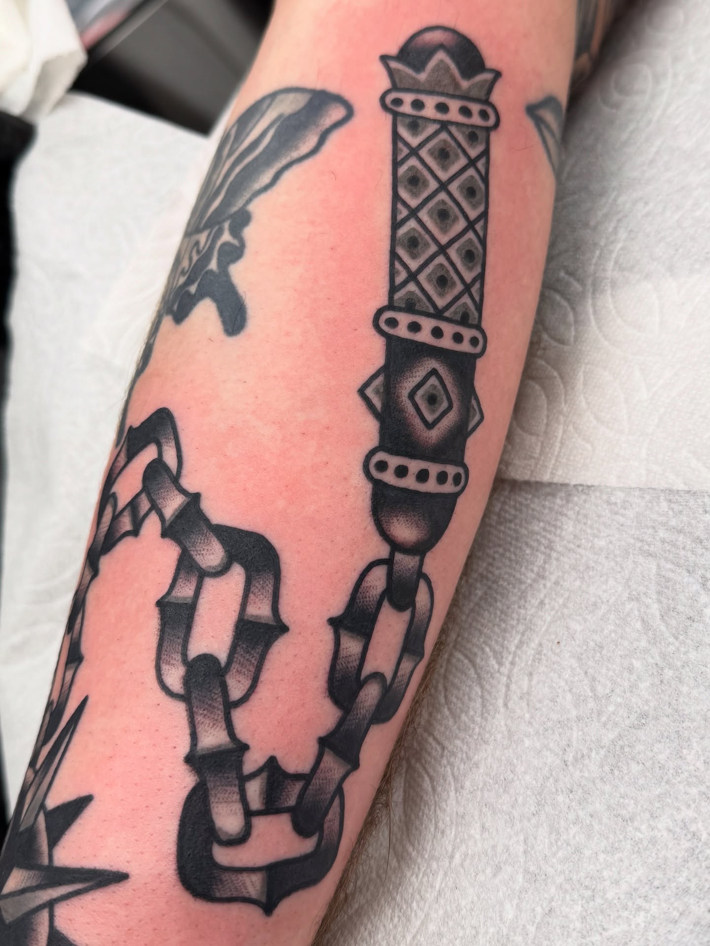 Chain and dagger black and grey tattoo on the forearm by Joey Burdette Tattoos