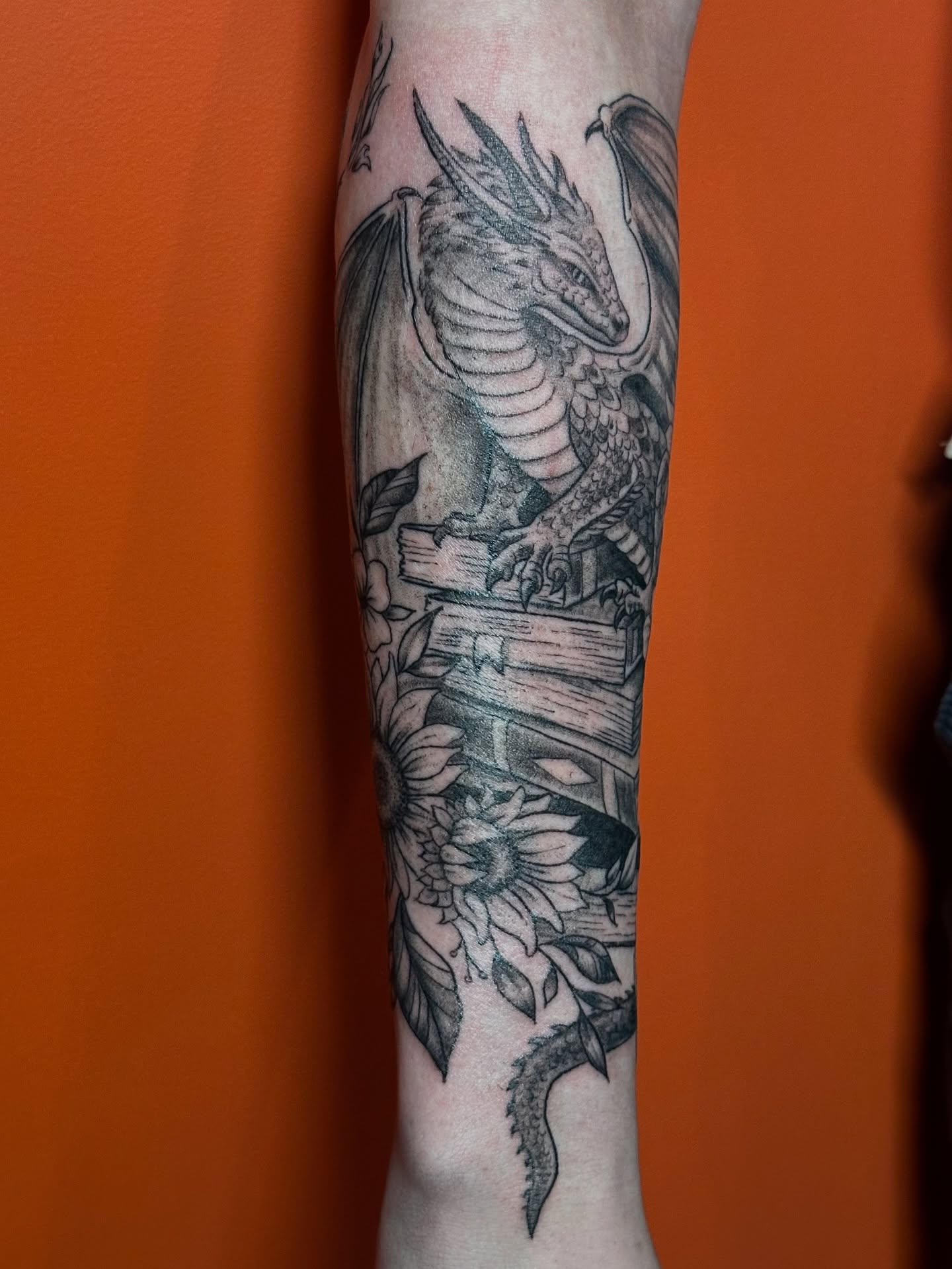 Dragon and sunflowers realism tattoo on the forearm by Lauren DeLizza