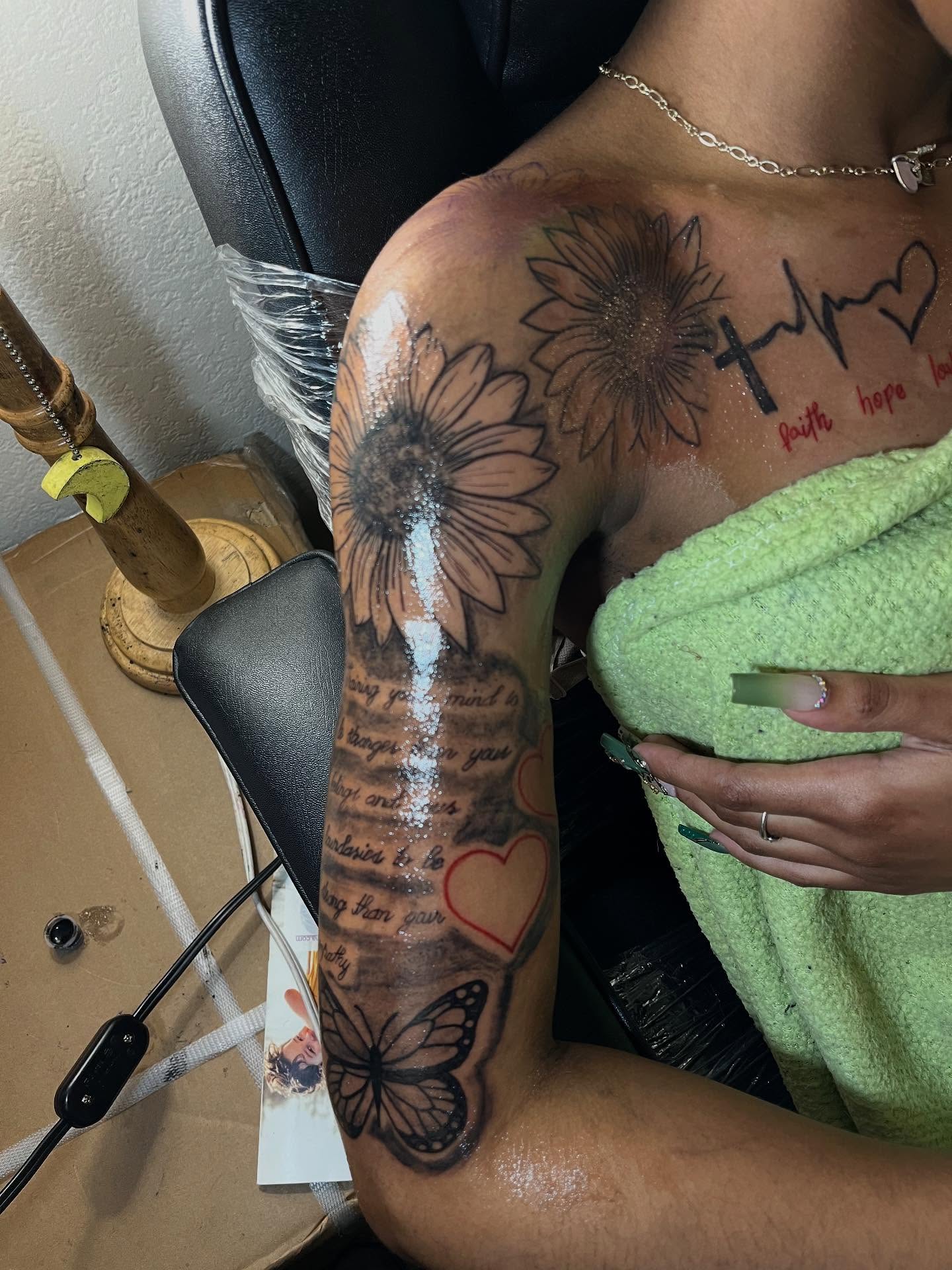Sunflowers, butterfly, hearts, cross, script black and grey tattoo on the upper arm by Dm To Book ๐, Charlotte, North Carolina