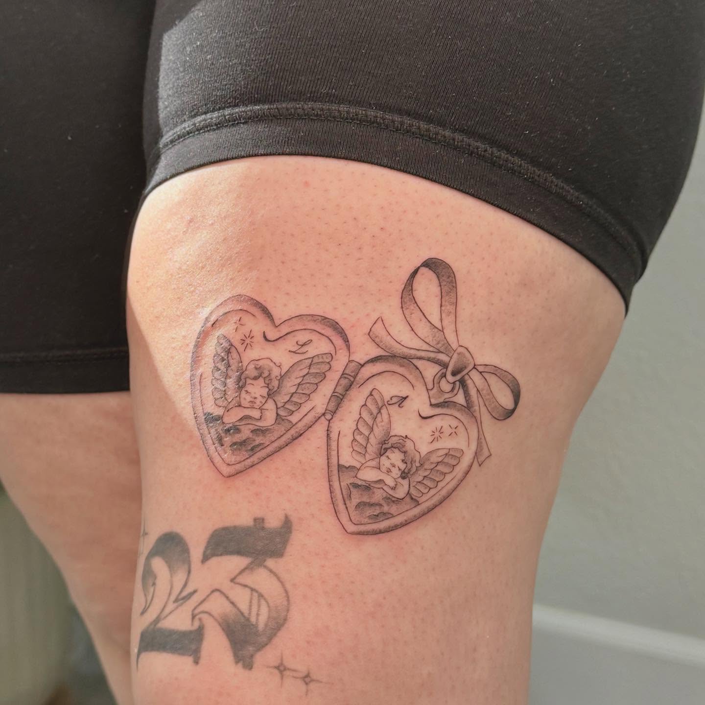 Hearts with cherubs black and grey tattoo on the thigh by Las Vegas Tattoo Artist