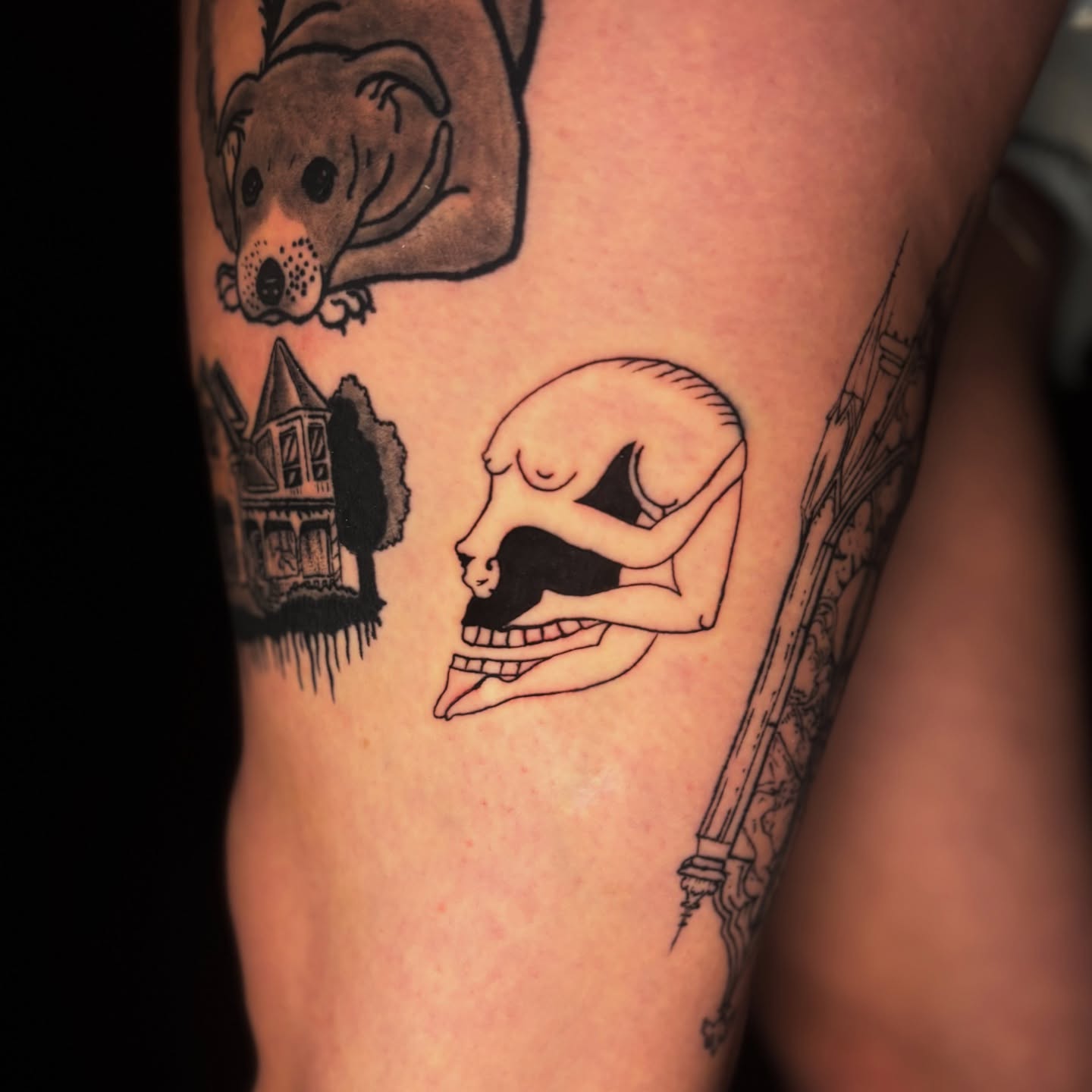 Dog, house, skull, tower black and grey tattoo on the thigh by Rachel