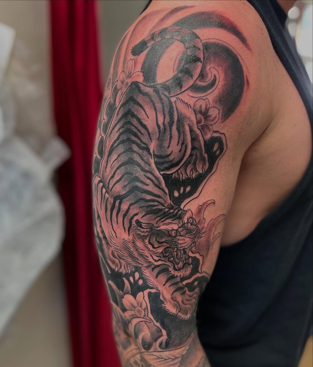 Tiger with flowers and waves Japanese tattoo on the upper arm by Randy Stout
