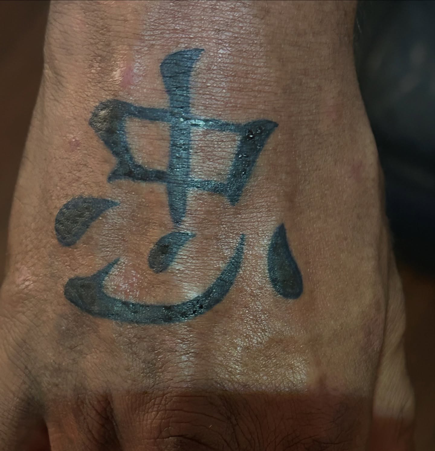 Chinese character lettering script tattoo on the hand by Trae