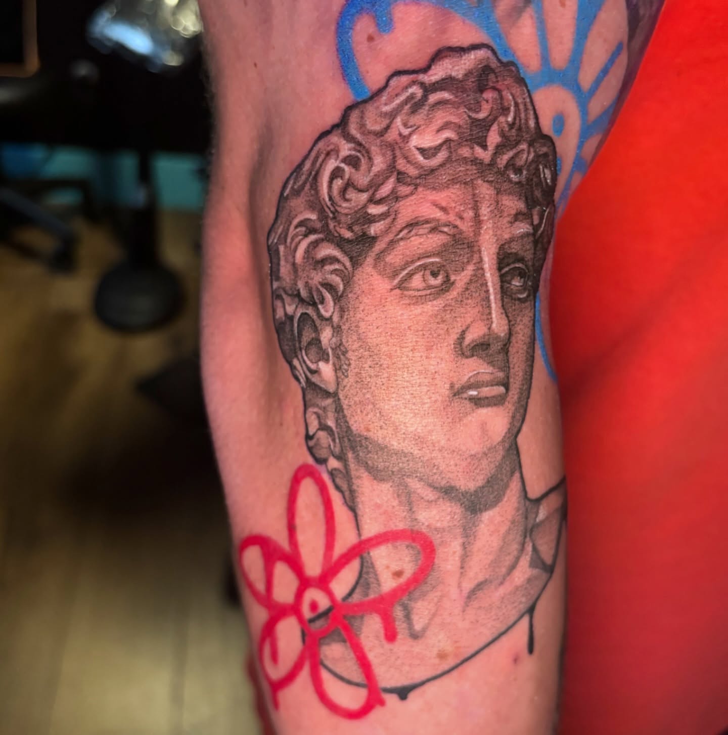 Bust of David statue with flower surrealism tattoo on the forearm by Kiwi🌱☀️