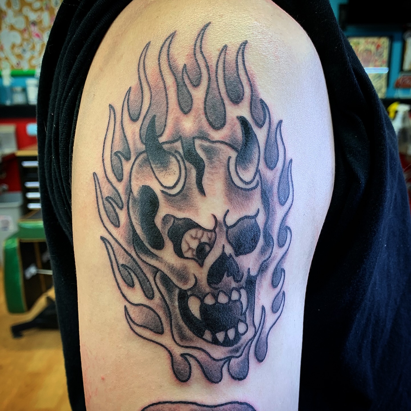 Flaming skull black and grey tattoo on the shoulder by Tattoos Las Vegas,NV