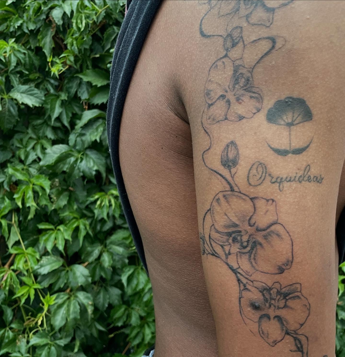 Orchids black and grey tattoo on the upper arm by Trinity
