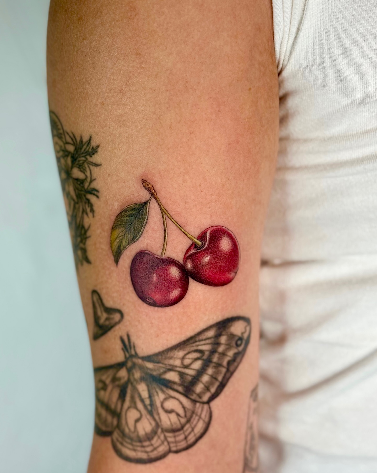 Cherries realism tattoo on the forearm by Mariana; Fine Line Tattoo Artist