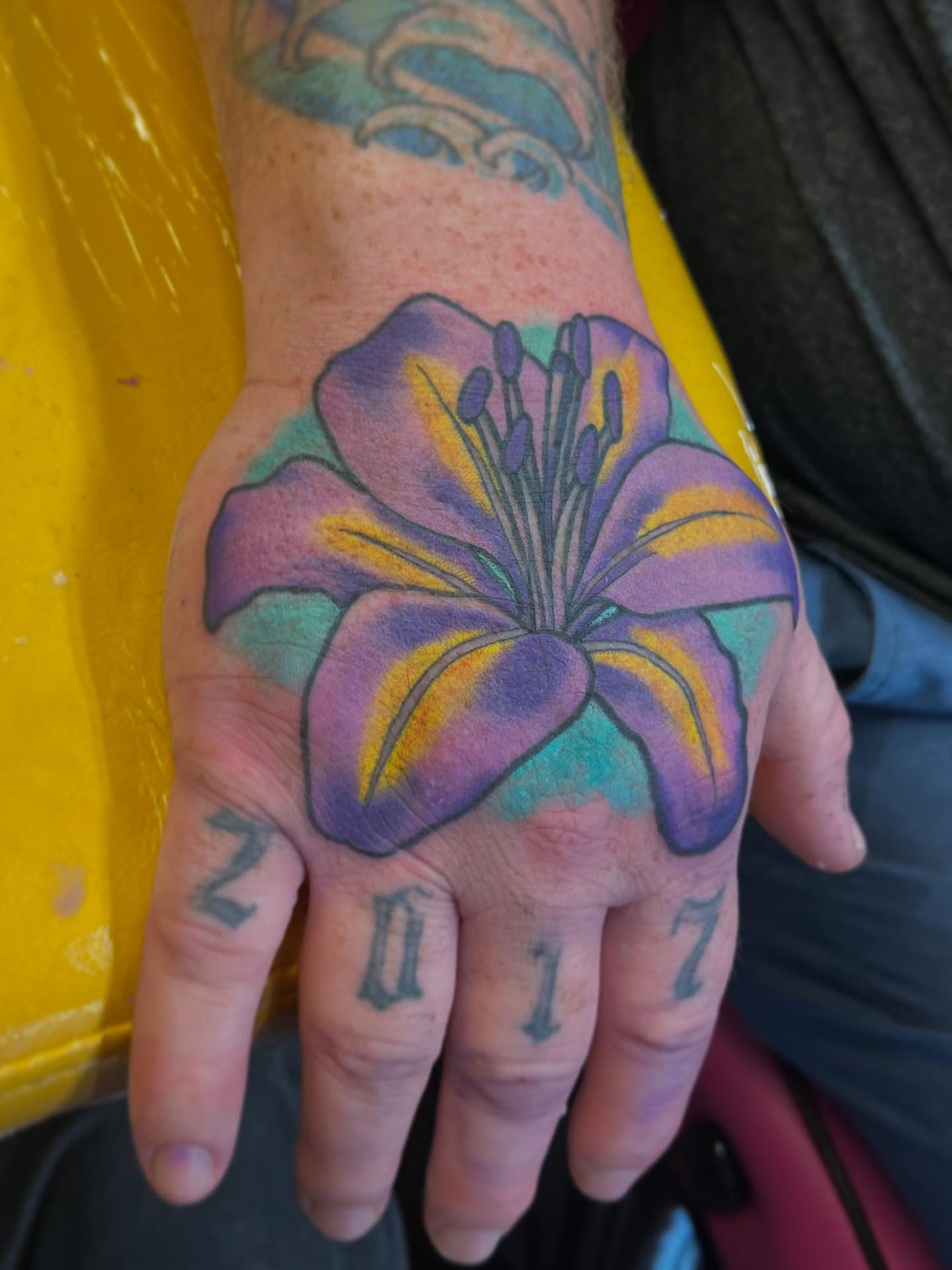 Lily new school tattoo on the hand by Riley McDonald