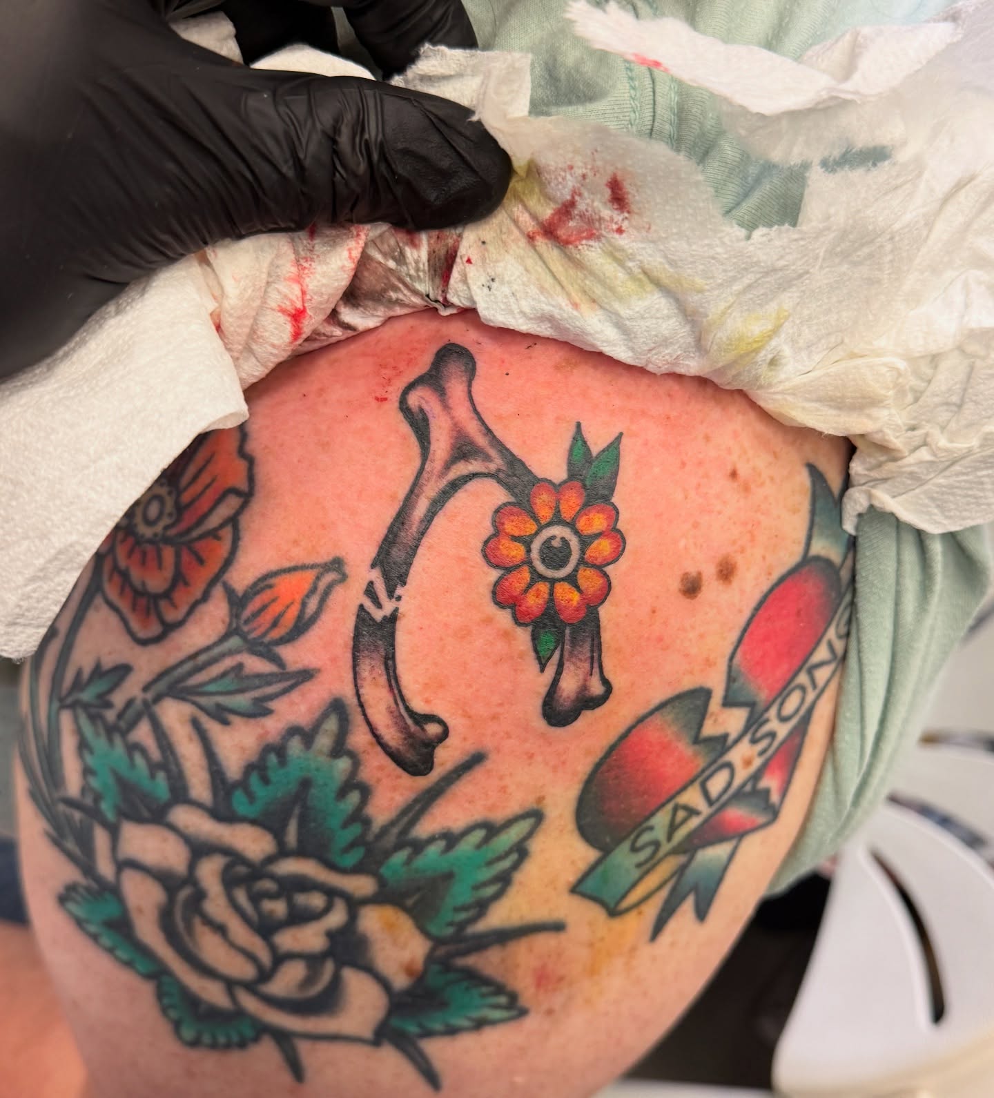 Flower and bone American traditional tattoo on the thigh by Angus Perfect, Philadelphia, Pennsylvania