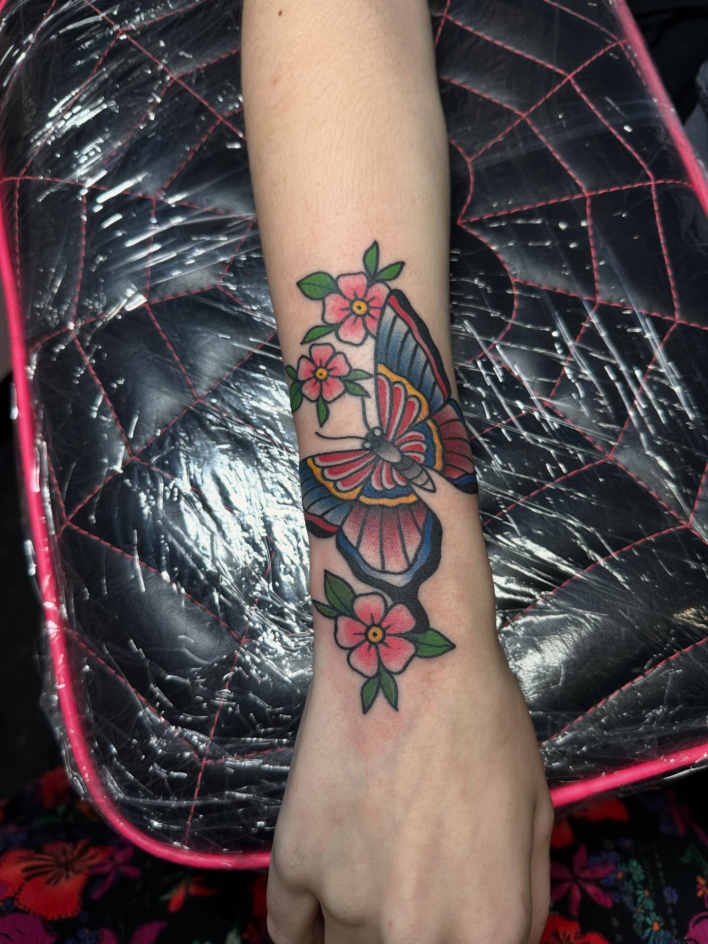 Butterfly and flowers American traditional tattoo on the forearm by Tattoo artist