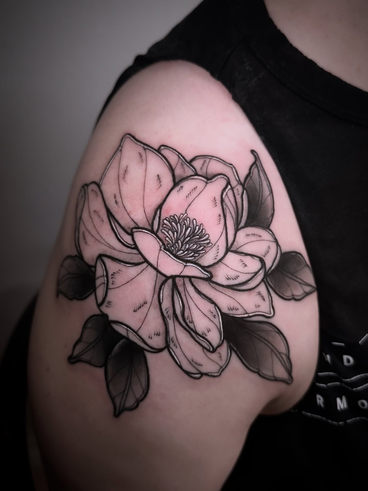 Lotus flower black and grey tattoo on the shoulder by Naysla Droguett