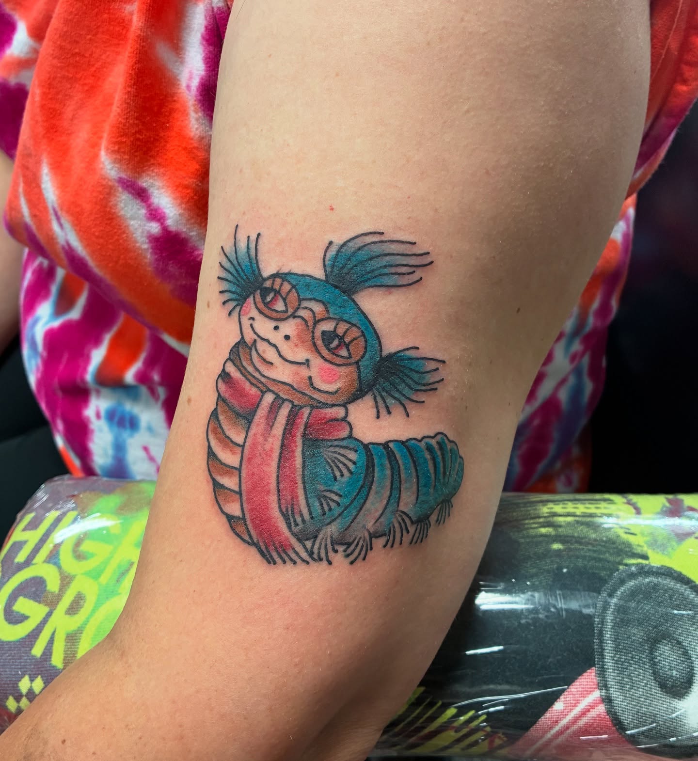 Worm with scarf illustrative tattoo on the forearm by Kennedy Cole
