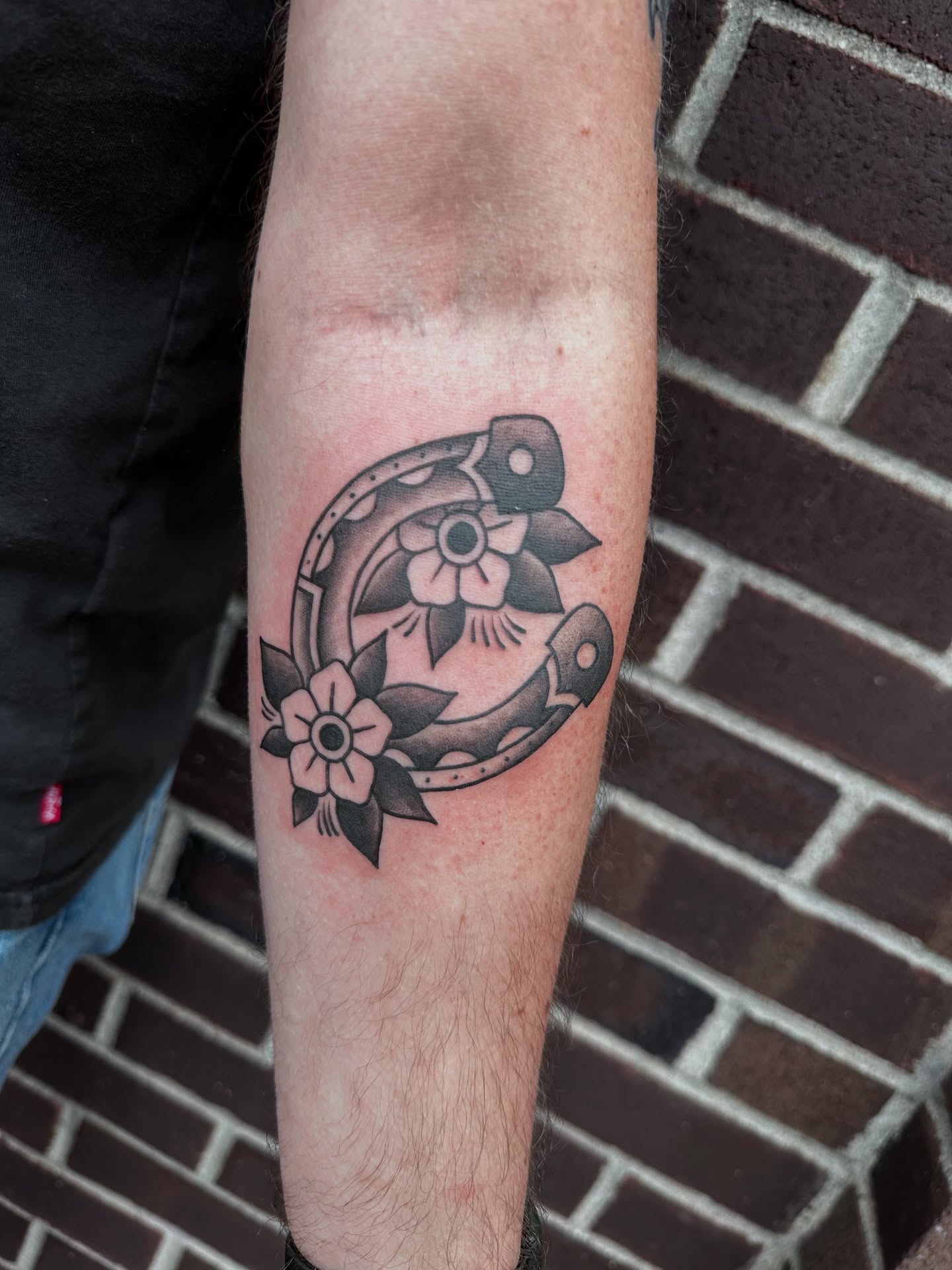 Horseshoe and flowers black and grey tattoo on the forearm by Hail Chaney, Somerville, Massachusetts