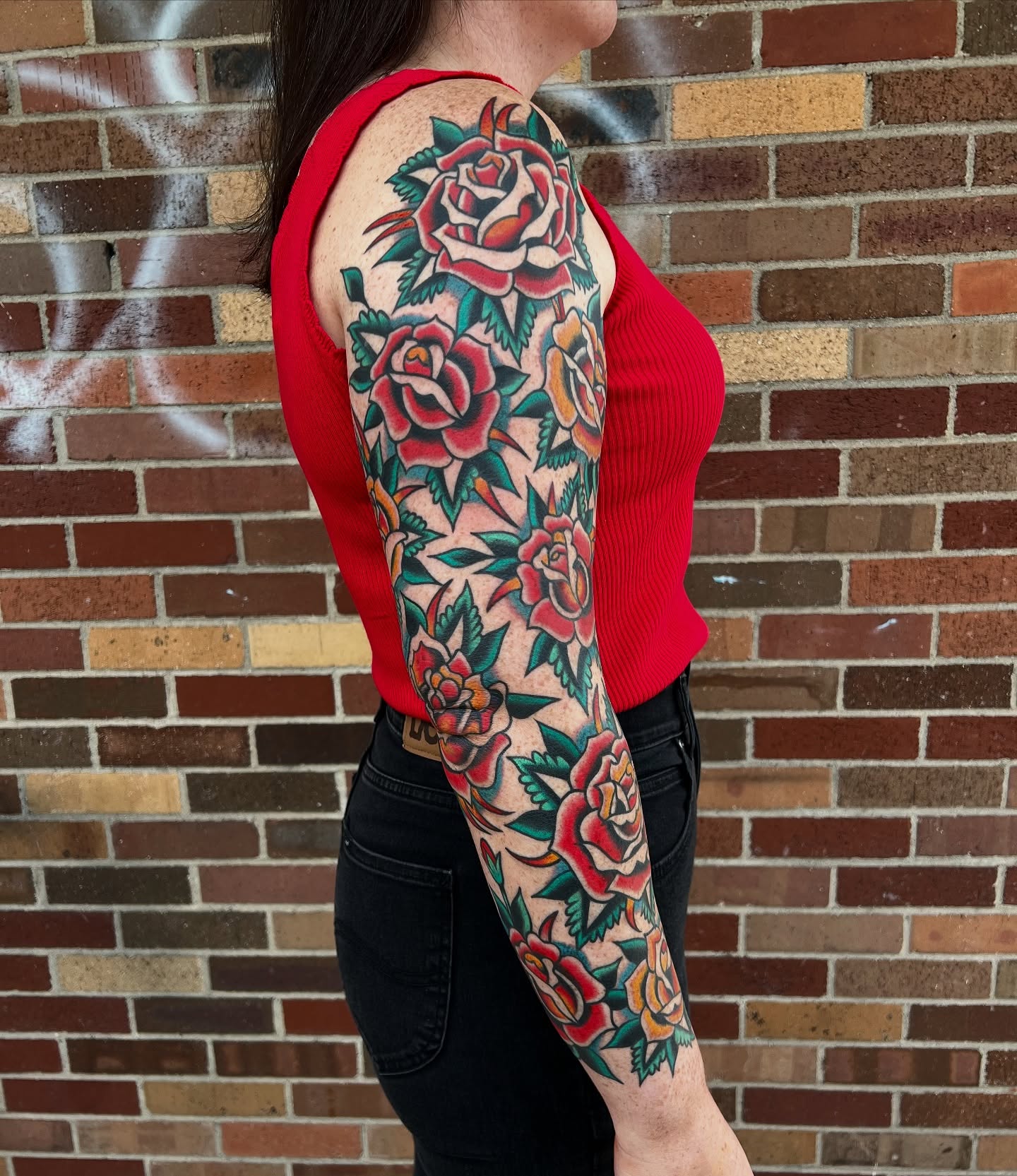 Roses American traditional tattoo on the upper arm by Nick Judkins Tattoo